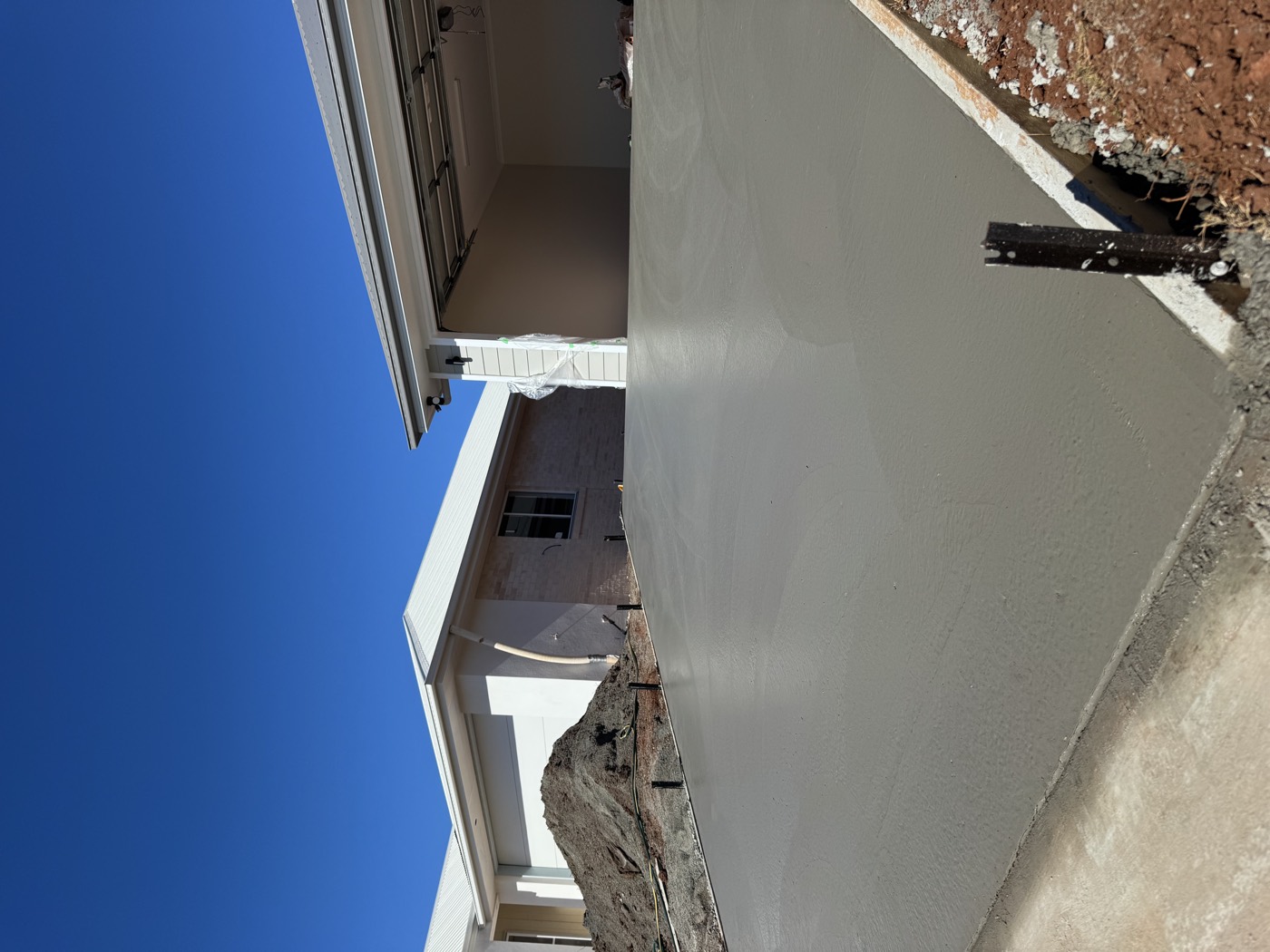 Freshly poured concrete driveway running down the side of a house
