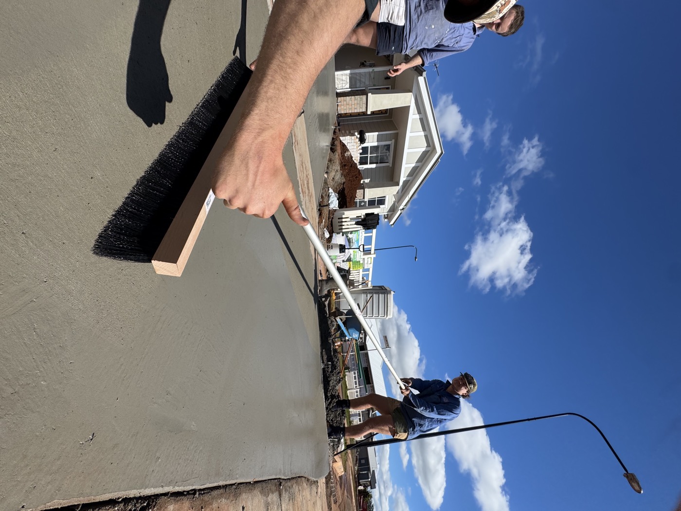 Broom being drawn across a fresh concrete slab